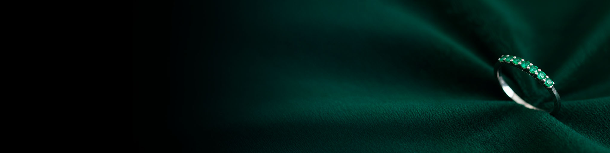 Alianza esmeralda oro blanco 18 quilates engastada piedras preciosas verdes sobre fondo textil verde joyería fina