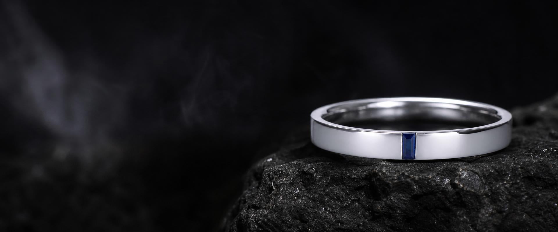 Bague alliance platine avec incrustation saphir bleu posée sur pierre noire, joaillerie fine haut de gamme