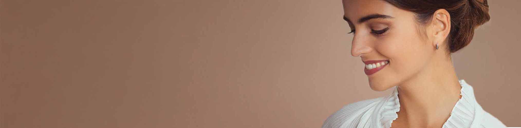 Pendientes argent elegantes portados por mujer sonriente, joyería fina moderna y refinada