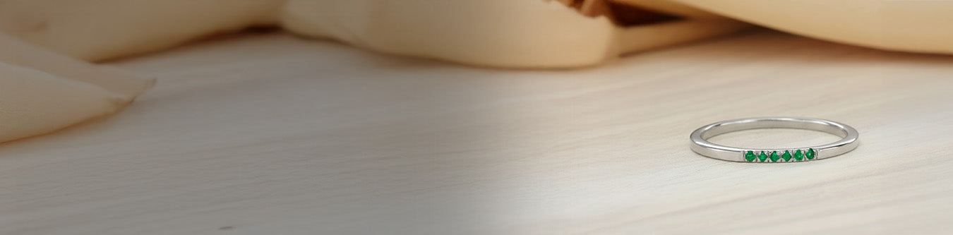 Alianza fina plata 925 engastada esmeraldas colección joyería contemporánea sobre fondo sedoso beige