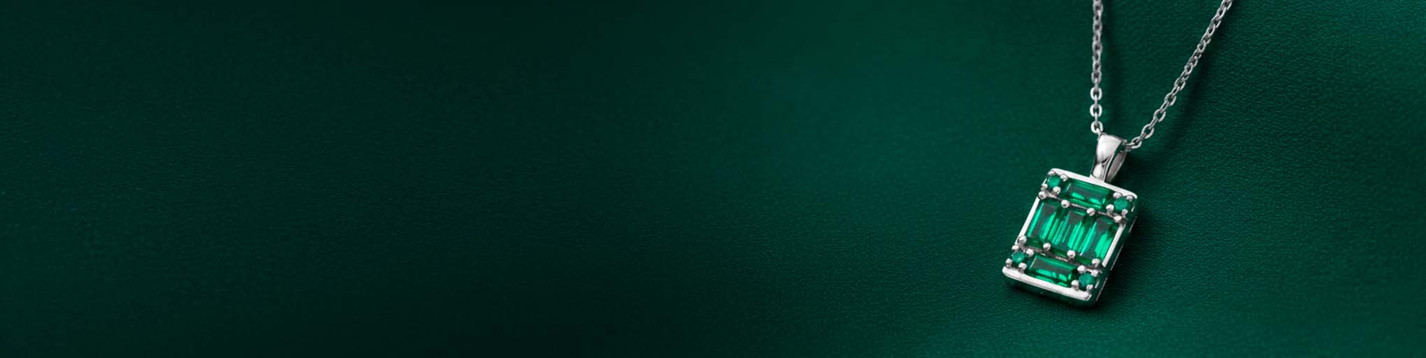Collar colgante esmeralda oro blanco 18 quilates engastada piedras preciosas verdes y diamantes sobre fondo verde joyería