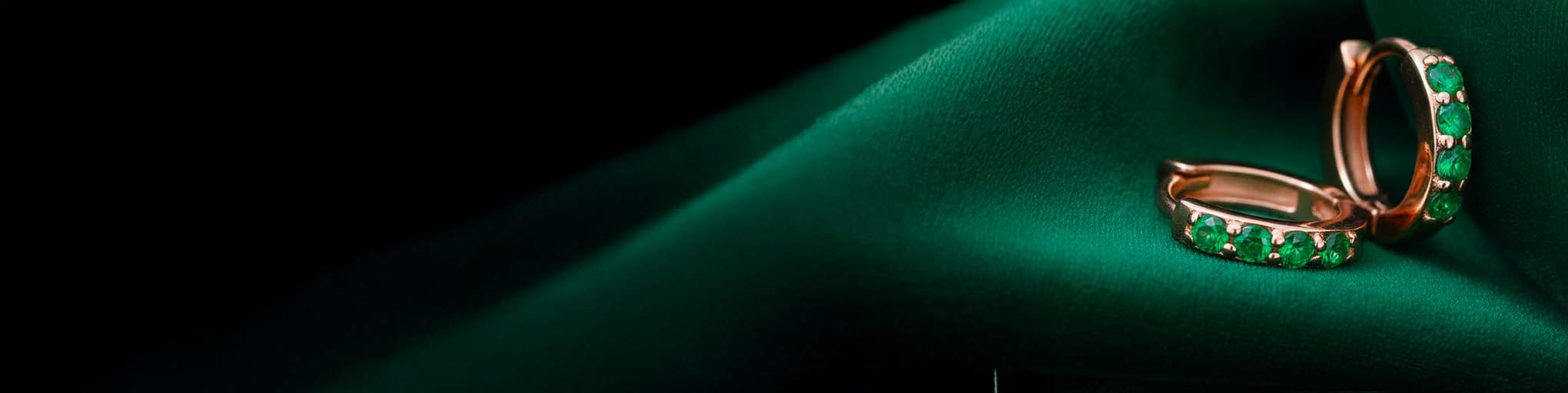 Aros esmeralda oro rosa 18 quilates, joyería fina con piedras preciosas verdes engastadas sobre fondo verde