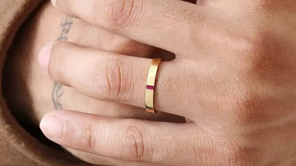 Bague de fiançailles homme Agni en or jaune 18 carats sertie d'un rubis baguette, portée à l'annulaire