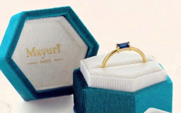 Anillo de zafiro en oro amarillo en su estuche de terciopelo Mayuri, junto a la gamuza de pulido