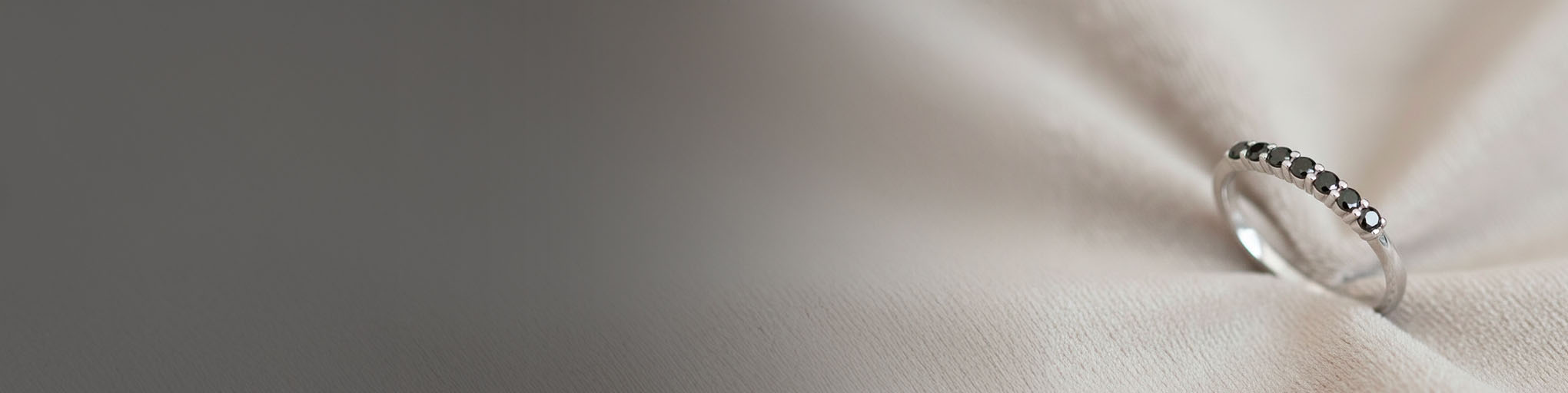 Alianza diamante negro oro blanco 18 quilates engastada piedras preciosas negras sobre fondo textil beige luminoso