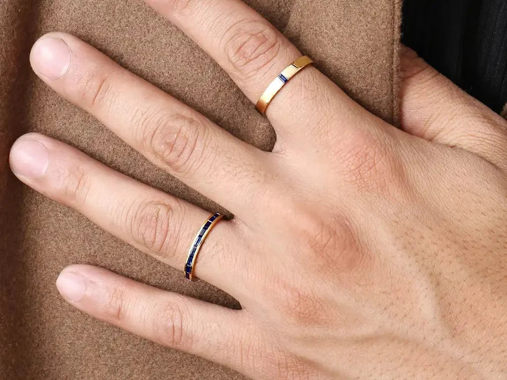 Dos anillos de compromiso para hombre Mayuri en oro amarillo de 18 quilates engastados con zafiros, llevados en la mano