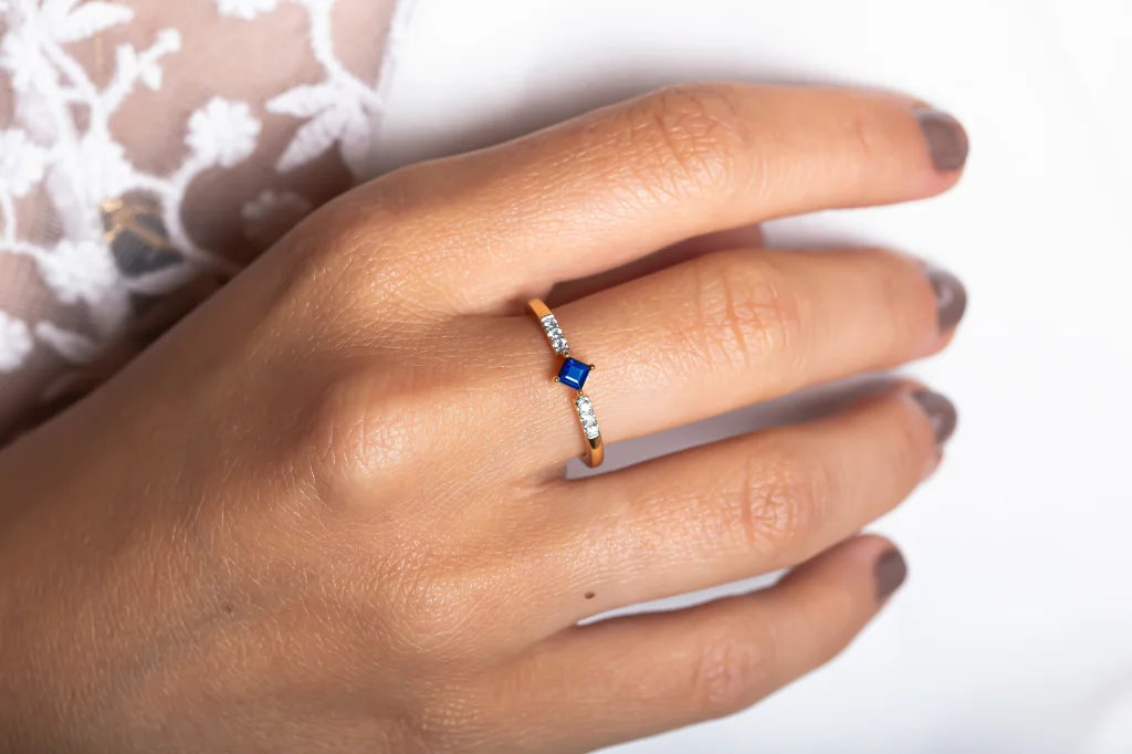 Anillo Kali en oro de 18k engastado con un zafiro talla princesa y diamantes, llevado en la mano