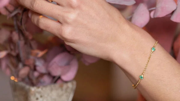 Pulsera Dhanya de esmeraldas y oro amarillo en la muñeca, idea de regalo para testigo de boda