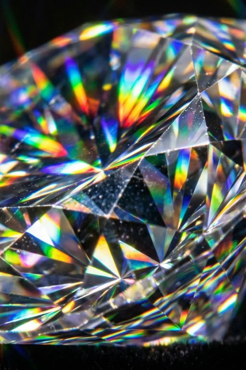 Macro des facettes d'un diamant taille brillant montrant la dispersion de la lumière et le feu