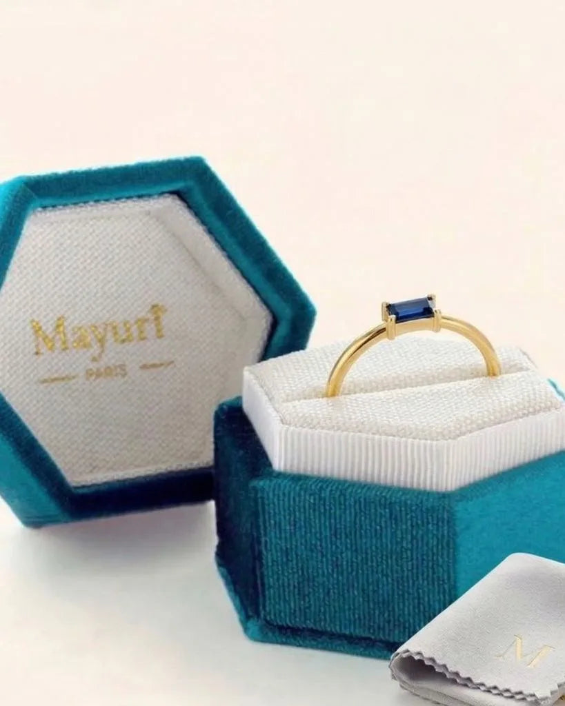 Anillo de zafiro en oro amarillo en su estuche de terciopelo Mayuri, junto a la gamuza de pulido
