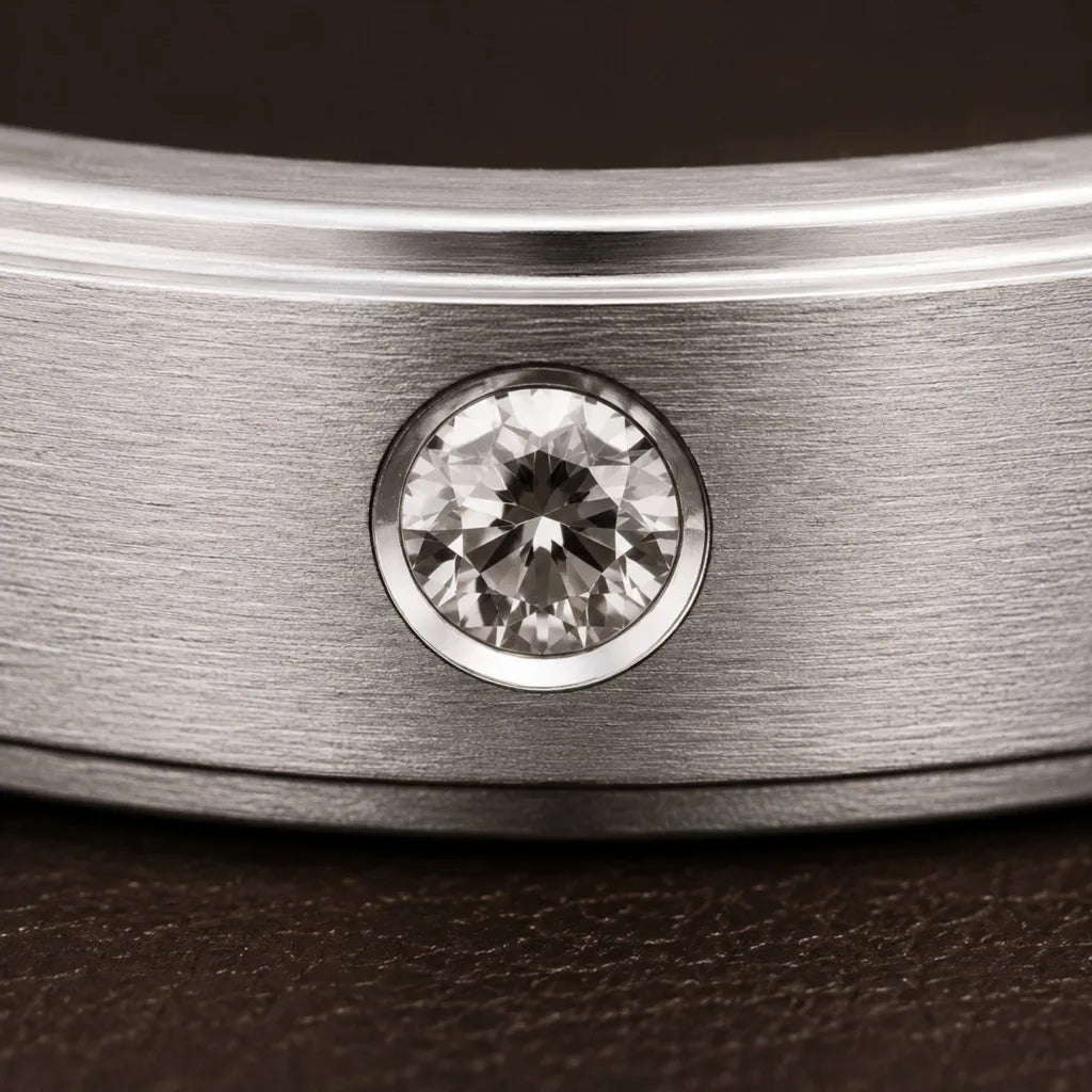 Diamante engastado en engaste cerrado sobre brazalete rigido de platino cepillado, primer plano de la característica textura mate del metal