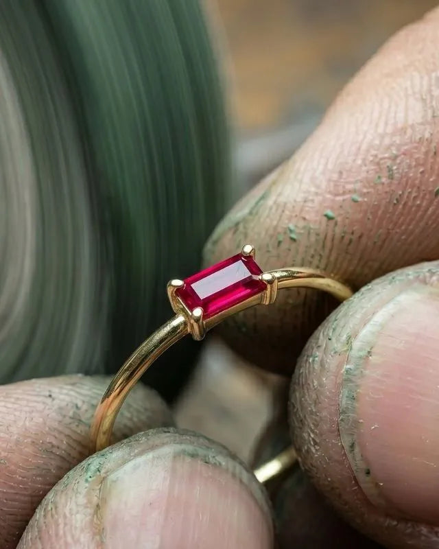 Joya engastada con piedra roja sostenida ante disco de pulido en taller Mayuri