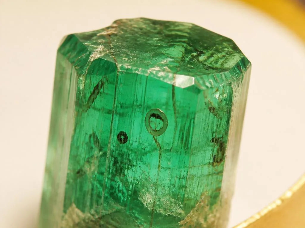 Cristal de esmeralda en bruto que muestra las inclusiones naturales y el jardín característico de la piedra