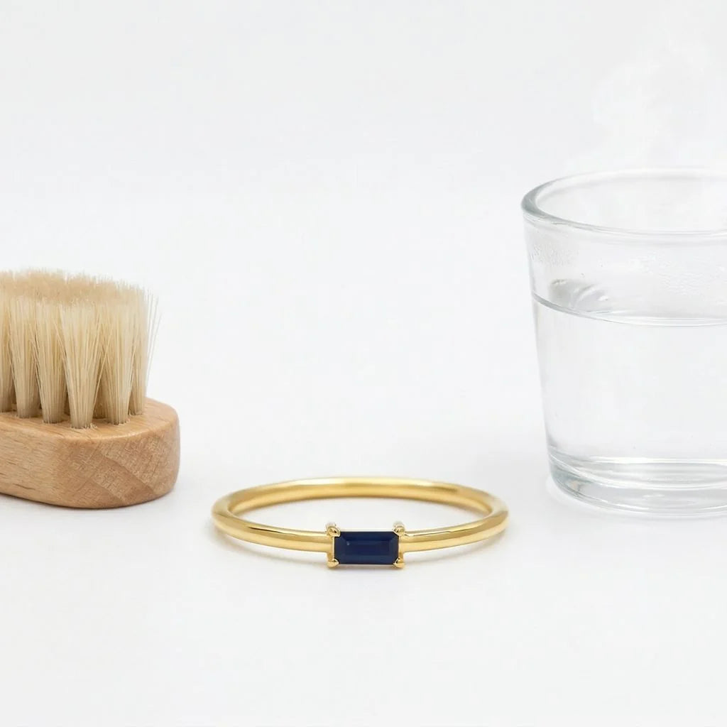 Anillo en oro amarillo de 18k engastado con un zafiro talla baguette, con cepillo suave y vaso de agua tibia