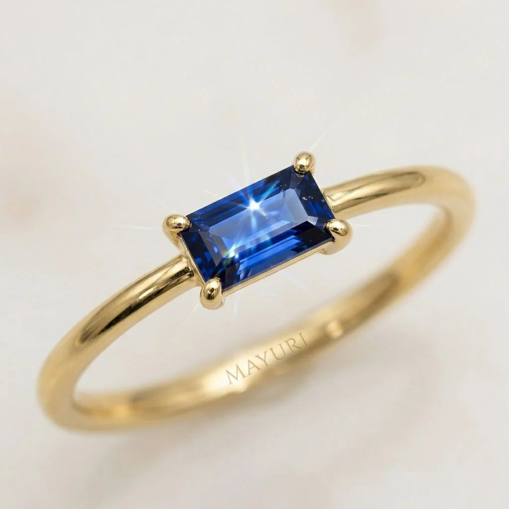Primer plano de un anillo Mayuri en oro amarillo de 18k engastado con un deslumbrante zafiro azul talla baguette