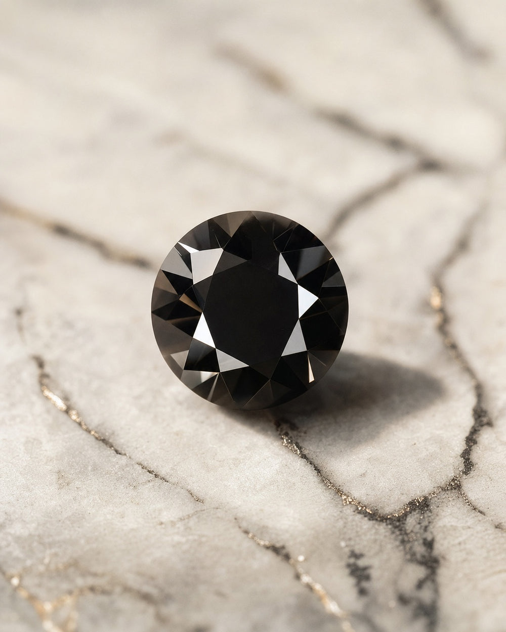 Diamant noir taille brillant posé sur marbre clair veiné, fort contraste