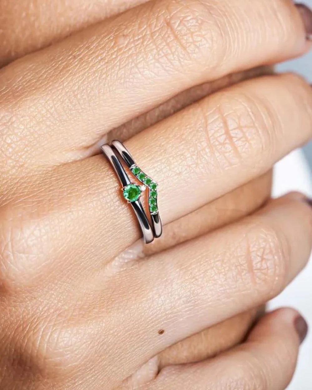 Bague de fiançailles sertie d'émeraudes portée à l'annulaire