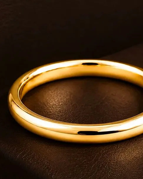 Alliance en or jaune 18 carats massif posée sur cuir brun foncé, lumière chaude soulignant l'éclat de l'or