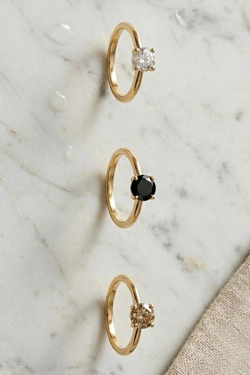 Tres solitarios en oro amarillo: diamante blanco, diamante negro y diamante champán